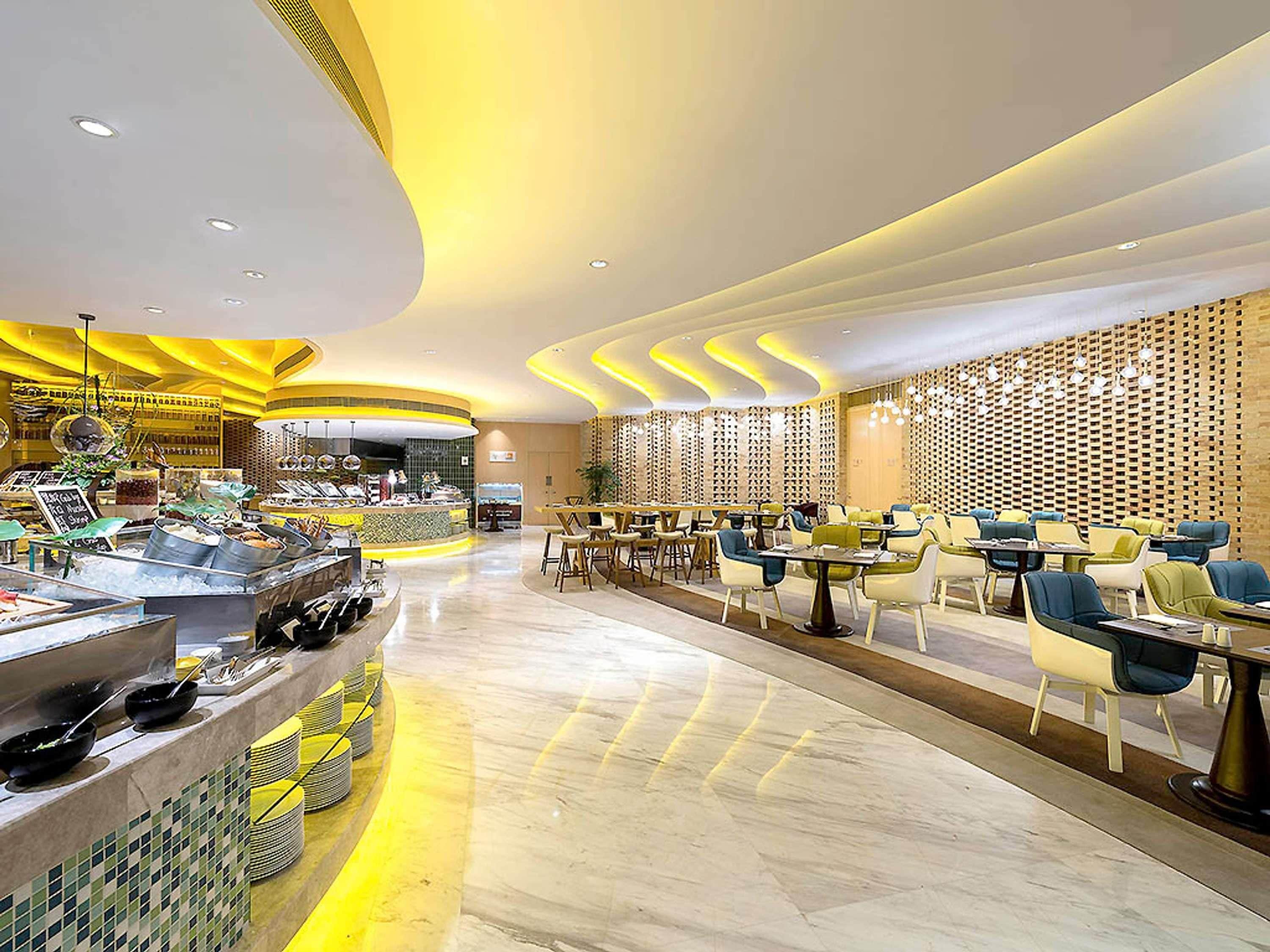 A modern restaurant with a buffet area, seating, and a decorative wall.