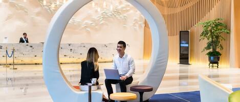 A modern reception area with a circular seating arrangement, a reception desk, and a potted plant.