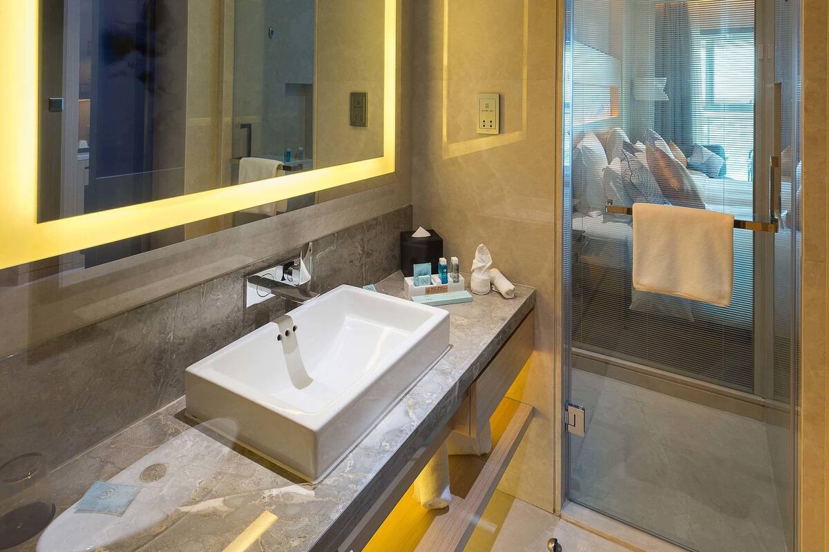 A modern bathroom with a large mirror, a sink, and a shower area.