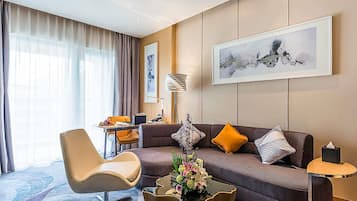 Een moderne hotelkamer met een bank, fauteuil en een eethoek.
