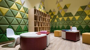 A modern room with geometric patterned walls, a central red and white circular seating area, and a wooden bookshelf. - Novotel Suzhou SIP (Suzhou)
