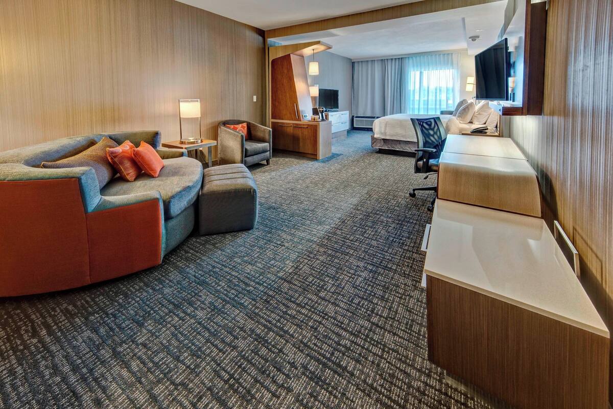 Een hotelkamer met een bank, bureau, bed en televisie.
