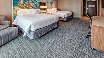 Ein Hotelzimmer mit zwei Betten, einem Schreibtisch, einem Stuhl und Teppichboden.