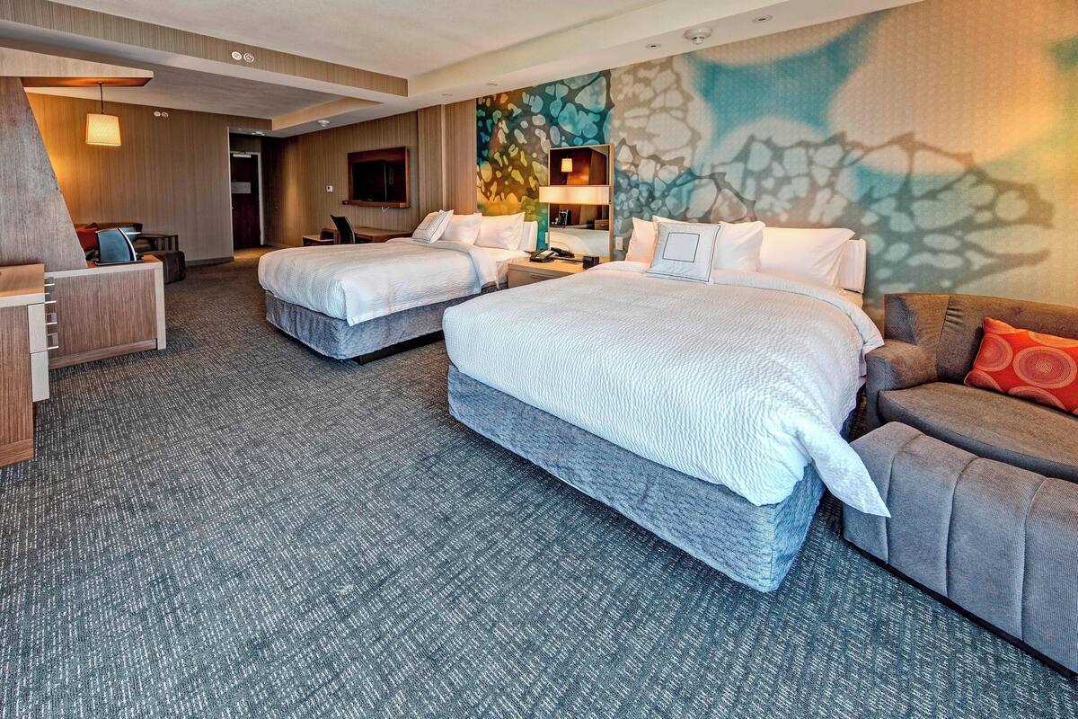 Een hotelkamer met twee bedden, een bank, een bureau en een televisie.