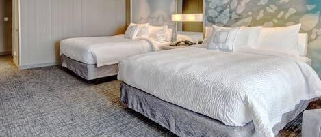 Quarto de hotel com duas camas, uma janela grande e uma parede com design texturizado.