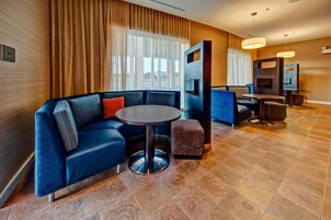 Un hall de hotel moderno con un sofá azul, una mesa redonda y una pantalla de televisión.