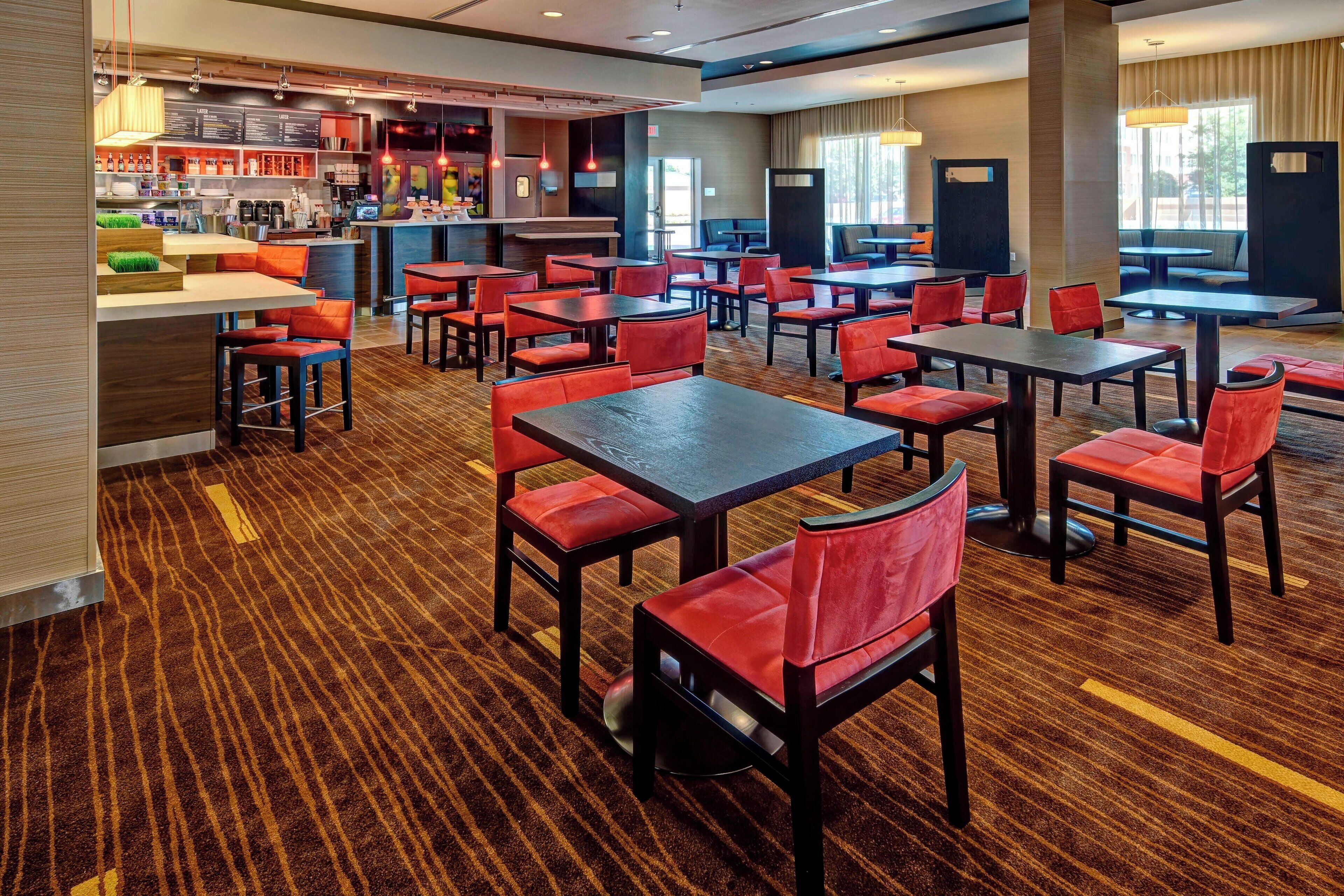 Um amplo hall de hotel com várias áreas de estar, um bar e uma mesa de recepção.