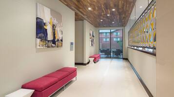 A hallway with a red bench, a white table, and artwork on the walls.