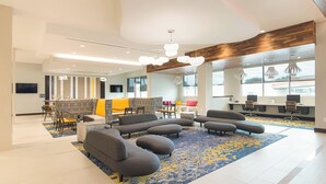 A modern lobby with a central seating area, a reception desk, and large windows.