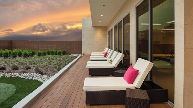 A rooftop terrace with sun loungers, a pool, and a view of the sunset.