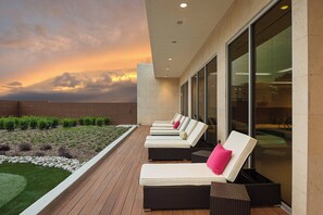 Une terrasse sur le toit avec des chaises longues, une piscine et une vue sur le coucher du soleil.