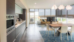 A modern kitchen with a Bosch microwave, a dining area with a wooden table and white chairs, and a large window offering a view of the outdoors.