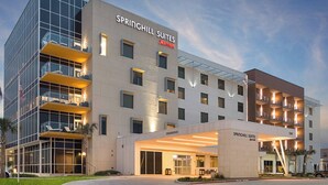 A modern hotel with a glass facade, multiple balconies, and a well-lit entrance.