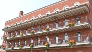 Ein mehrstöckiges Backsteingebäude mit Balkonen, die jeweils mit Blumenkästen geschmückt sind.