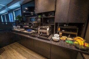 Una cocina moderna con electrodomésticos de acero inoxidable, una zona de café y una cesta de frutas.