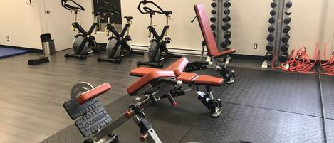 A gym with weightlifting equipment, exercise bikes, and a door marked "EXIT".