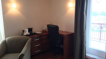 A room with a desk, chair, and a window with curtains.