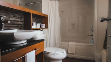 Un baño con inodoro blanco, lavabo con espejo, zona de ducha y bañera.