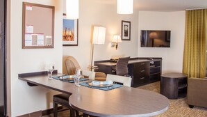 Habitación de hotel con comedor, televisión de pantalla plana, escritorio y sofá.