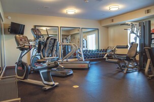 Un gimnasio con cintas de correr, elípticas y pesas sueltas.