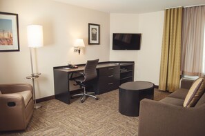 A hotel room with a desk, two chairs, a TV, and a window with curtains. - Candlewood Suites Denver North - Thornton by IHG (Thornton)