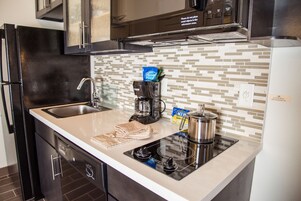 Una cocina moderna con un lavamanos de acero inoxidable, una cafetera, un hervidor y un microondas.
