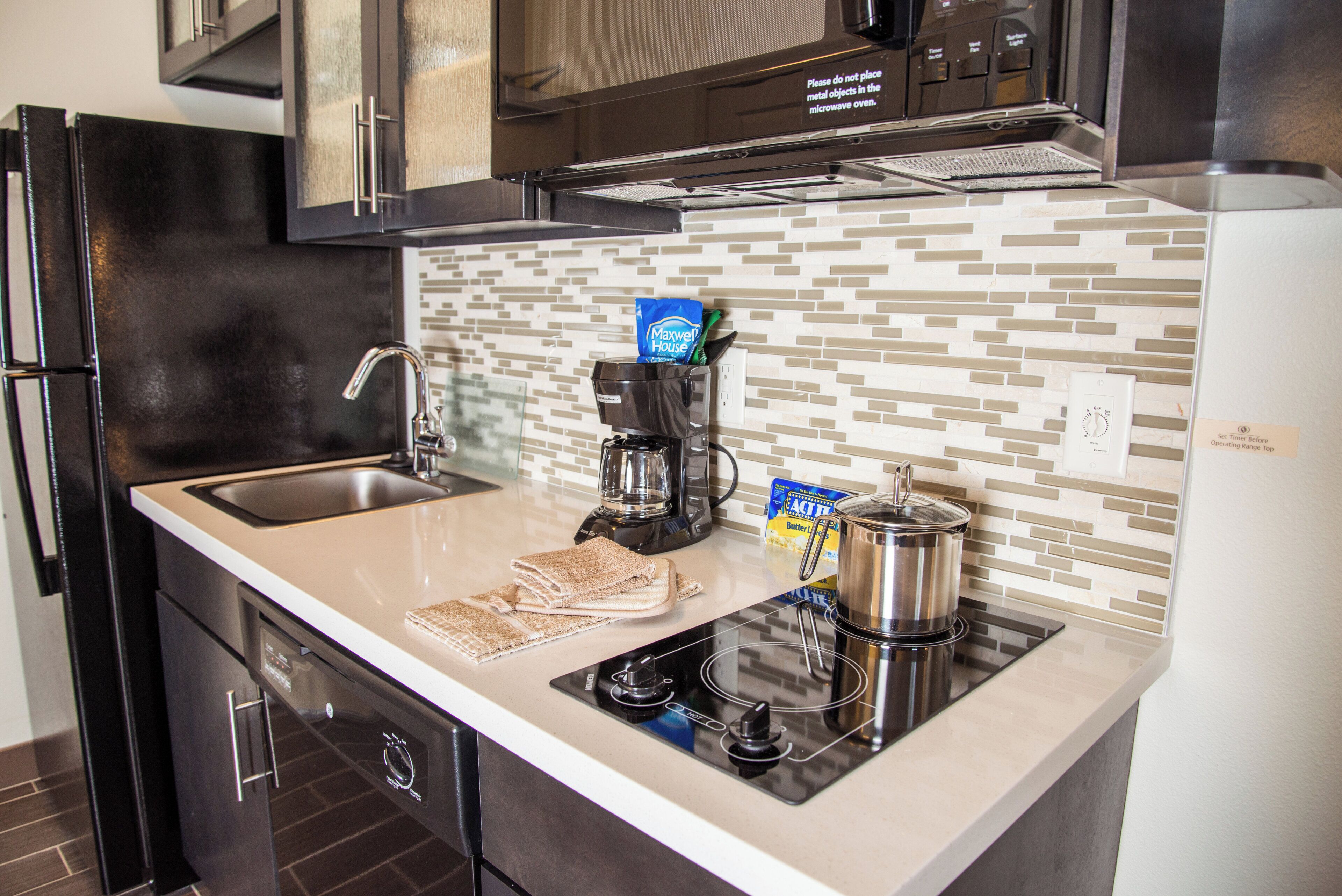 A modern kitchen with a built-in microwave, coffee maker, and a kettle on the countertop.