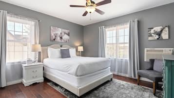 A bedroom with a bed, nightstands, a ceiling fan, and two windows with curtains.