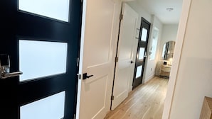 A hallway with a black door on the left and a white door on the right, leading to a kitchen area. - New Haven Inn (Solvang)