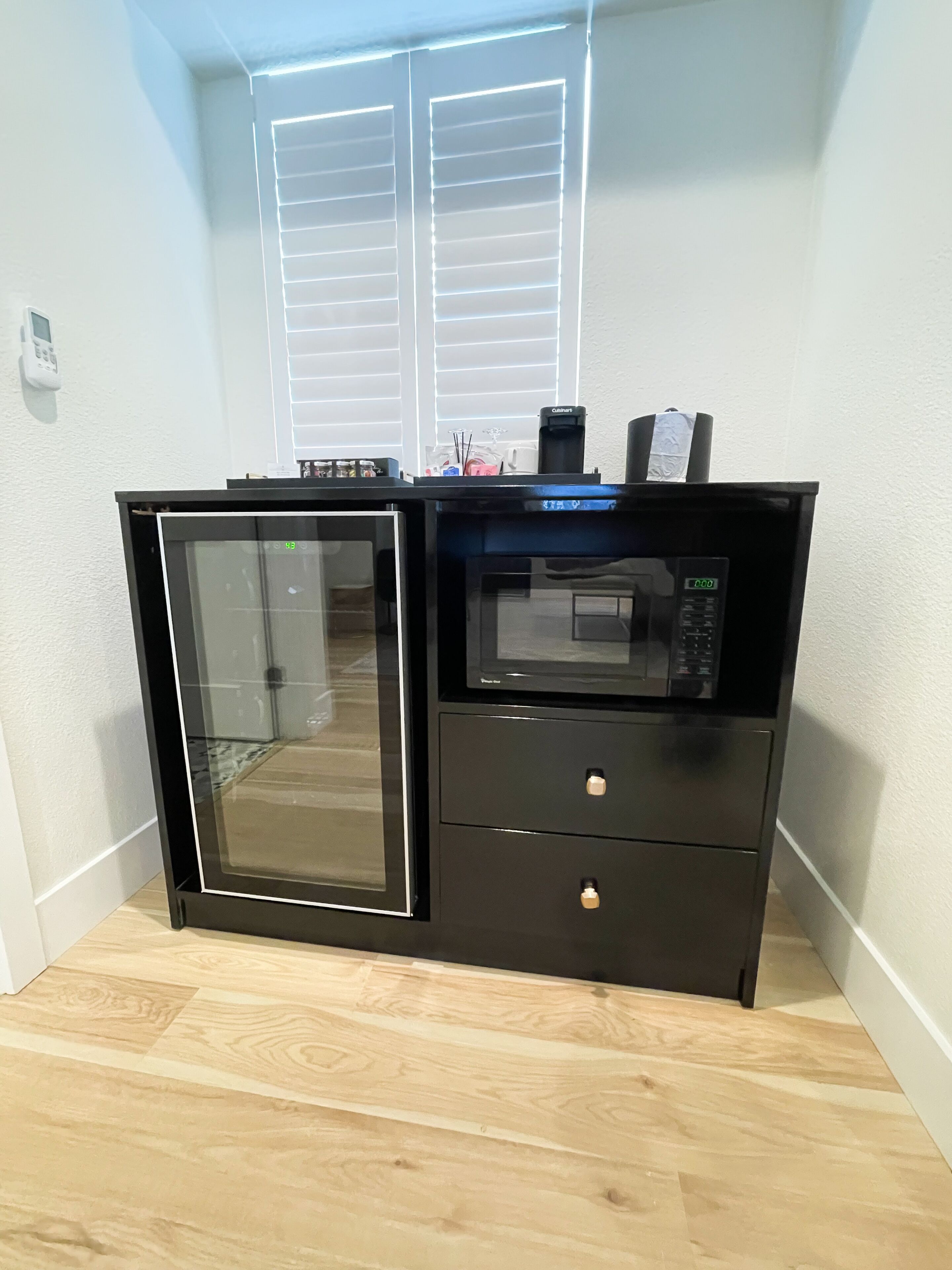 Uma cozinha compacta equipada com micro-ondas, mini-geladeira e forno de porta de vidro.