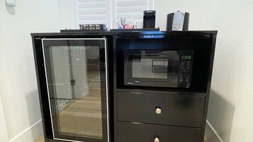 Uma cozinha compacta equipada com micro-ondas, mini-geladeira e forno de porta de vidro.