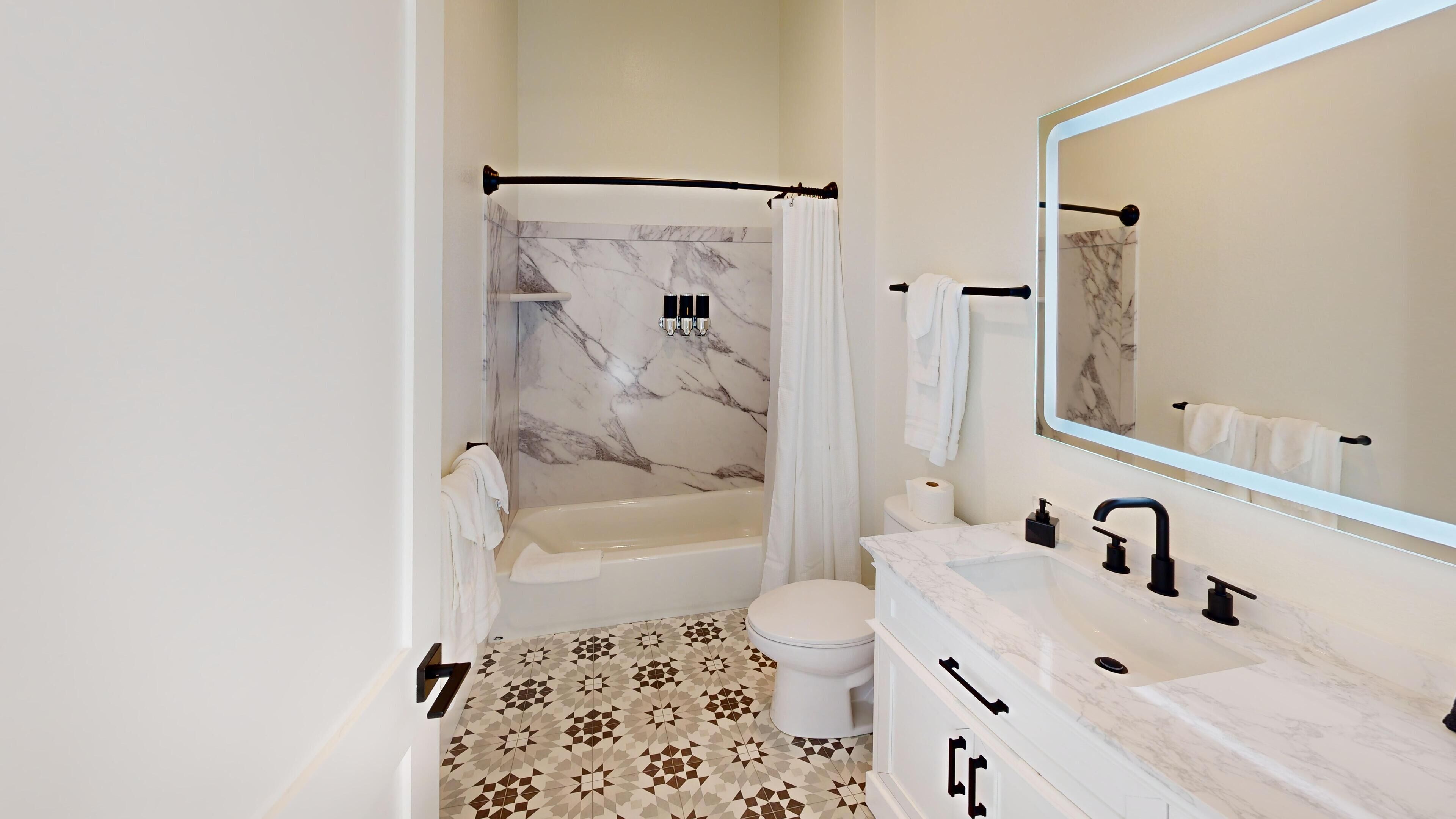 Een moderne badkamer met een bad, toilet en wastafel.
