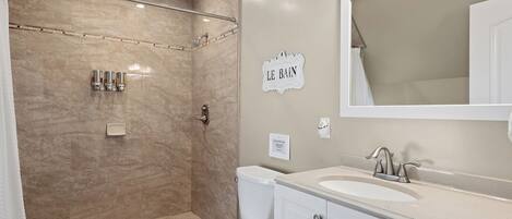 A bathroom with a shower, toilet, sink, and a sign that reads "LE BAIN".