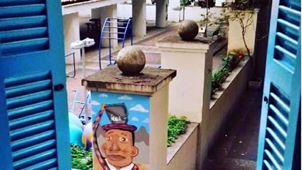 A balcony with a view of a street, a mural, and a decorative stone. - Solar Hostel Beach Copacabana (Rio de Janeiro)
