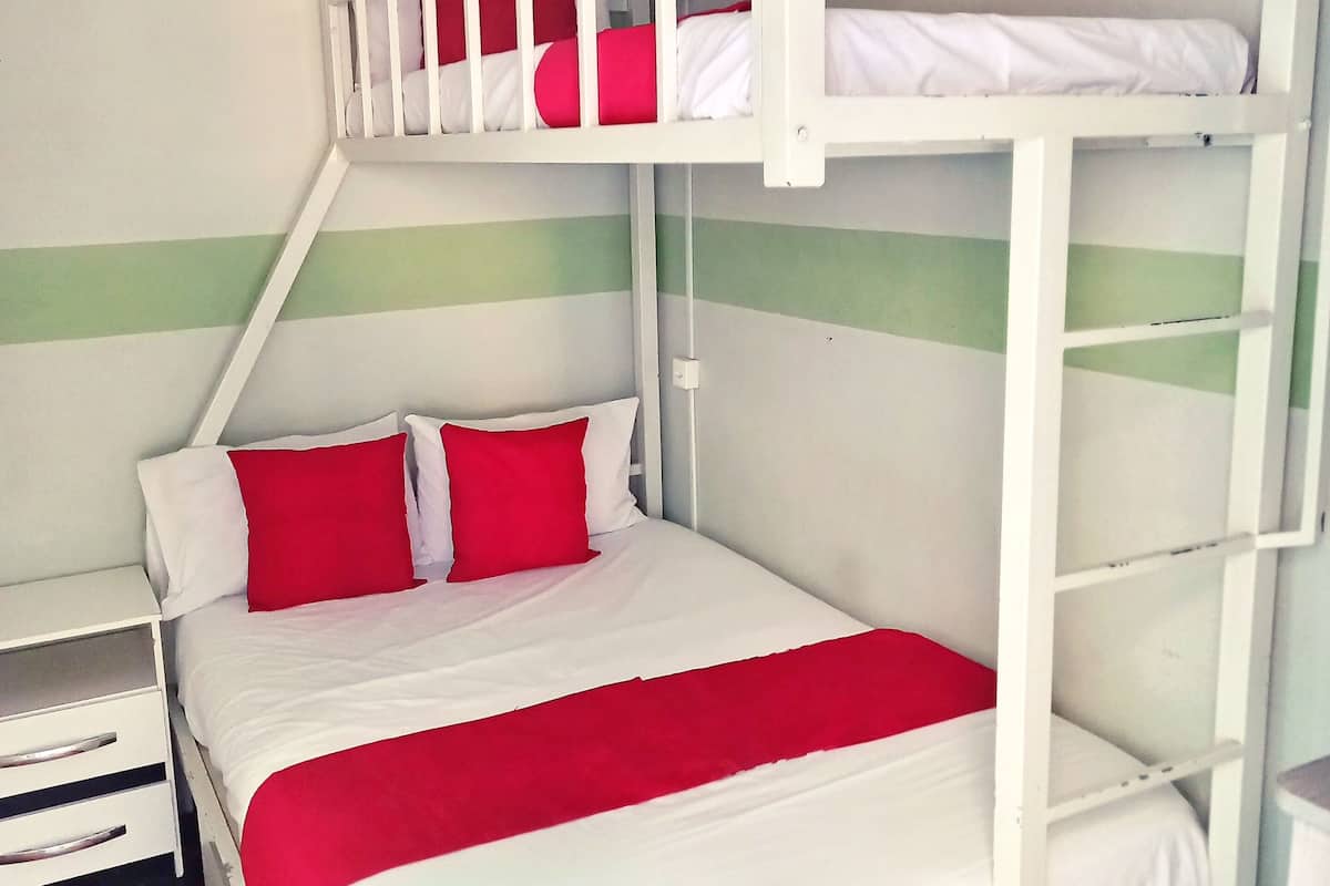 A bunk bed room with a white and red color scheme, a nightstand, and a dresser.