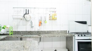 A kitchen with white tiles, a granite countertop, a stove, and a hanging rack with utensils. - Solar Hostel Beach Copacabana (Rio de Janeiro)
