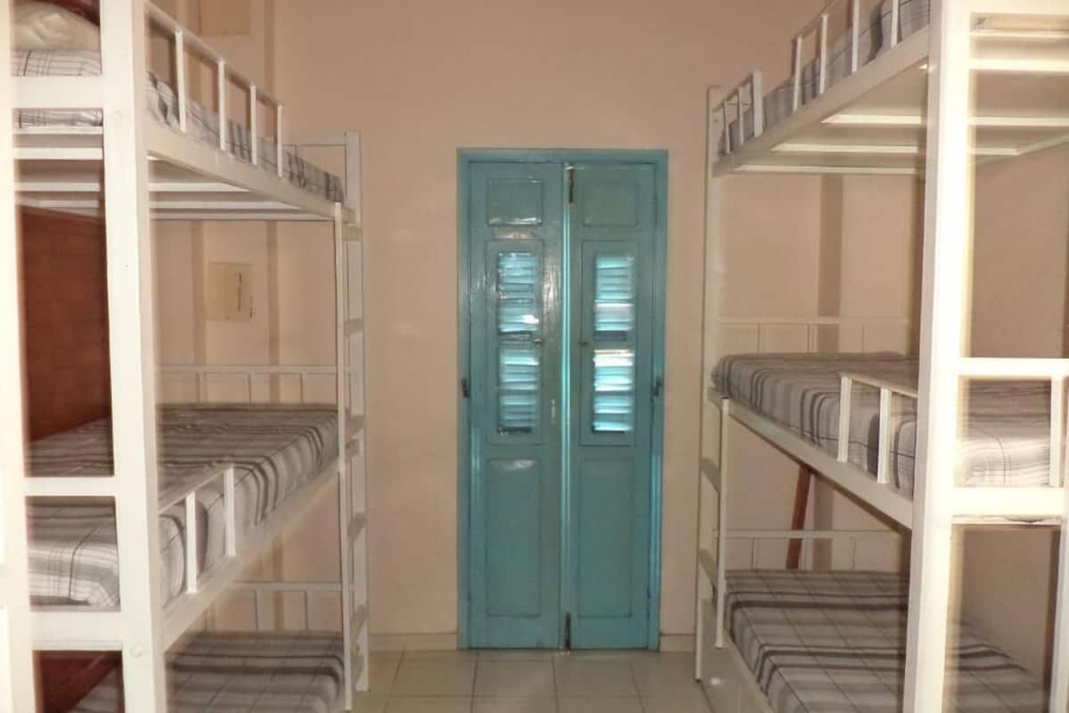 A corridor with bunk beds on either side leading to a blue door.