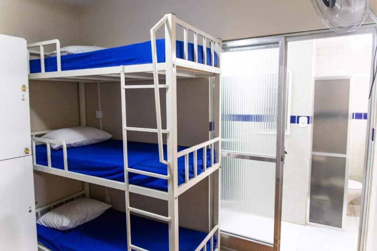 A bunk bed room with a white wardrobe and a sliding glass door leading to a bathroom.
