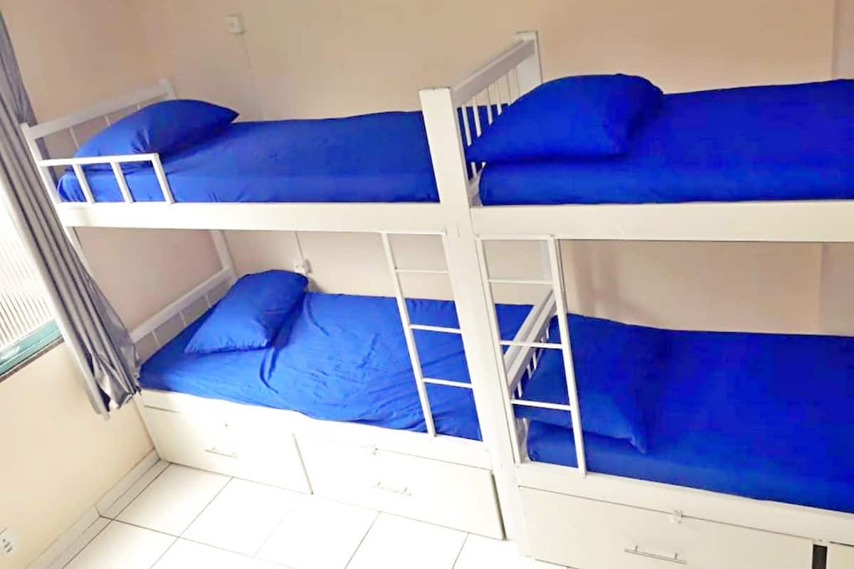 A bunk bed room with three beds, each with blue bedding.
