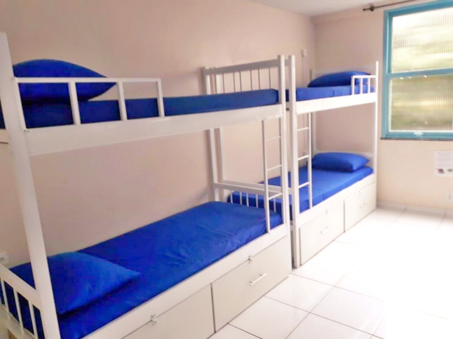 A bunk bed room with white railings and blue bedding.