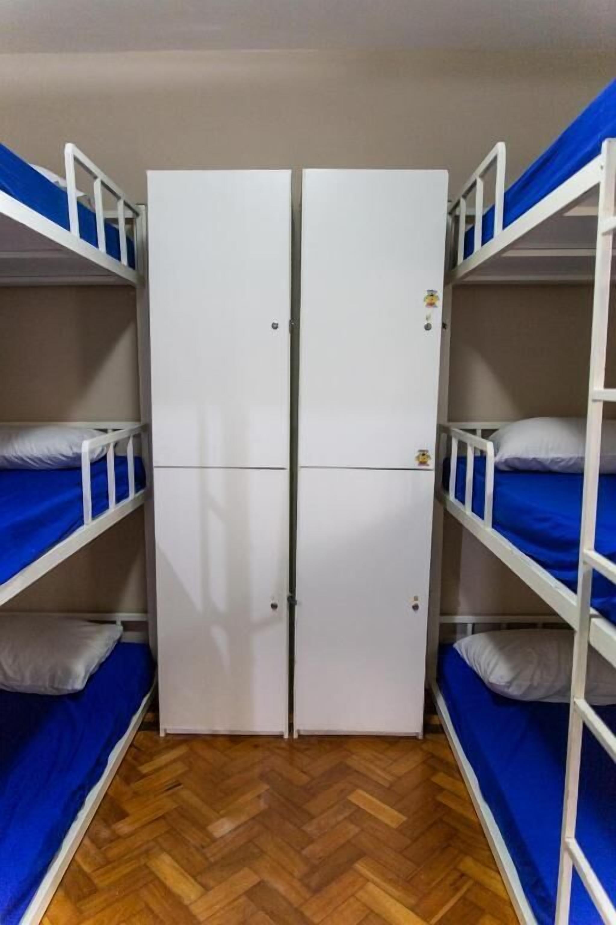 Asuntolan huone, jossa on kerrossängyt, vaatekaappi ja kalanruotokuviollinen puulattia.