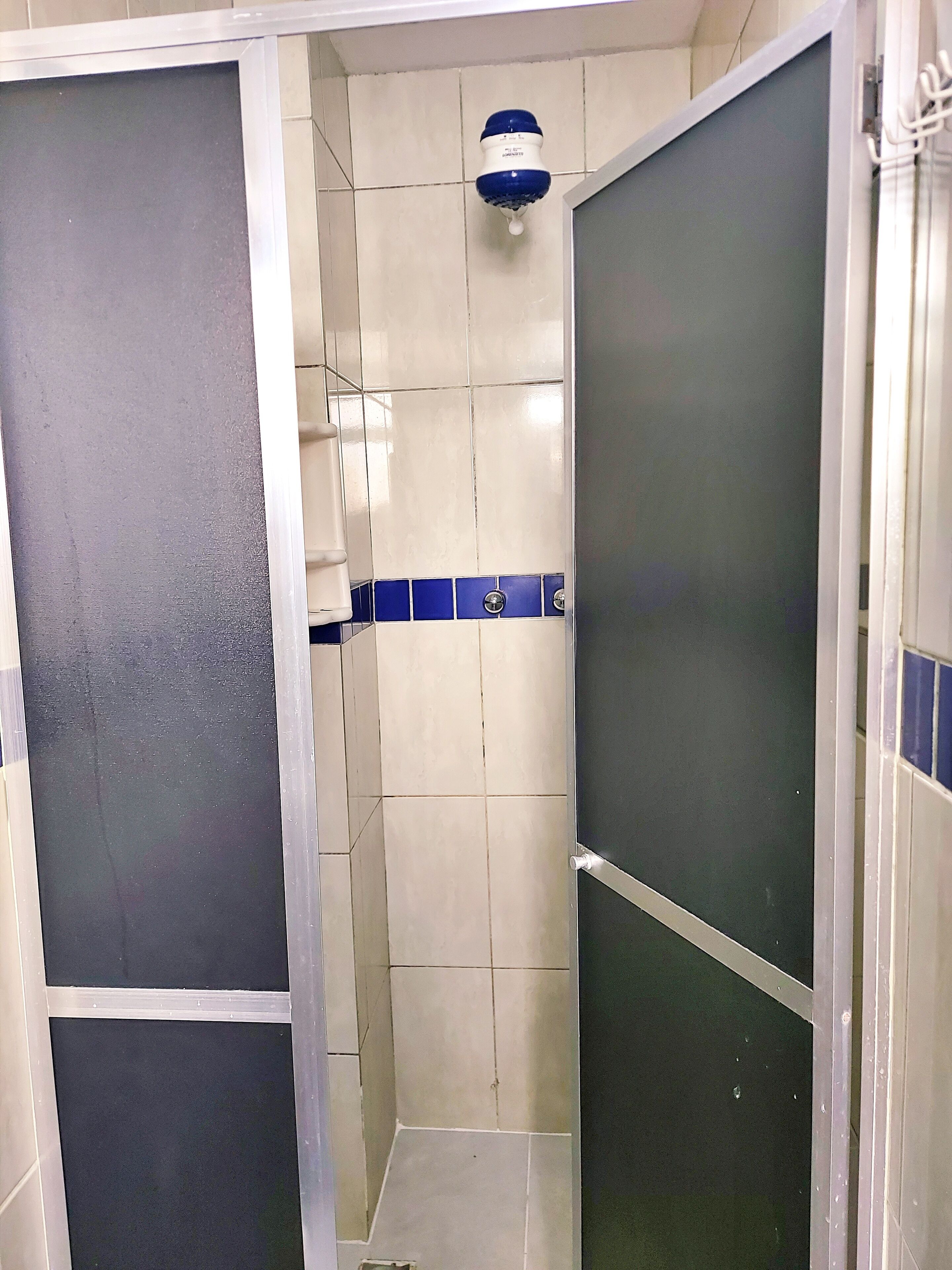 A bathroom with a shower area, tiled walls, and a blue and white tiled accent wall.