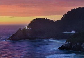 A coastal landscape with a lighthouse and a building on a cliff, overlooking the sea. - Three Rivers Casino Resort (Florence)