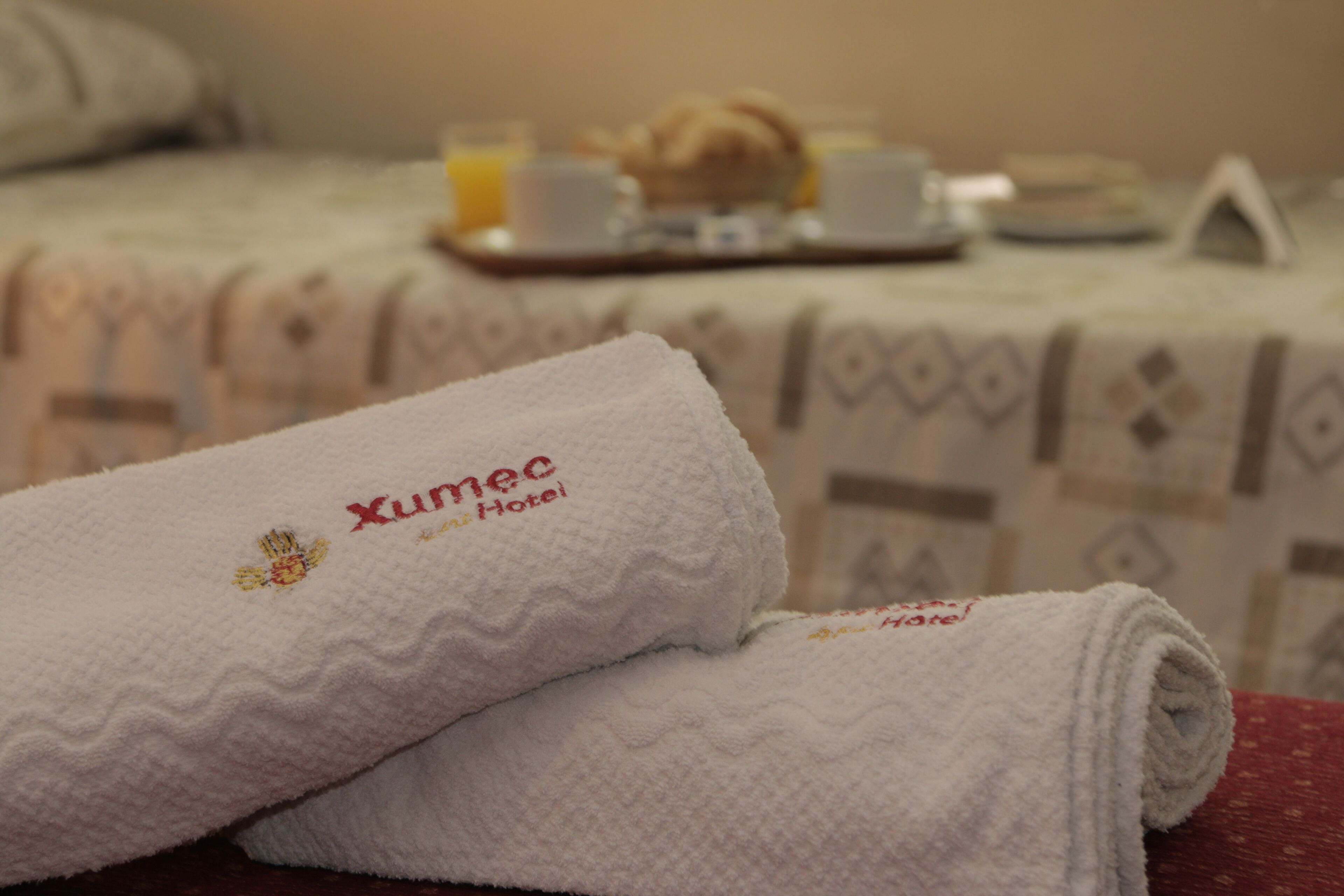 A neatly folded white towel with embroidered text indicating it is from the Xumec Hotel.