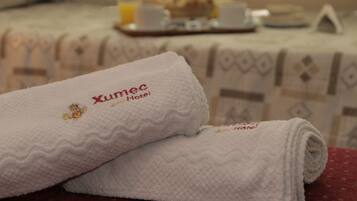 A neatly folded white towel with embroidered text indicating it is from the Xumec Hotel.