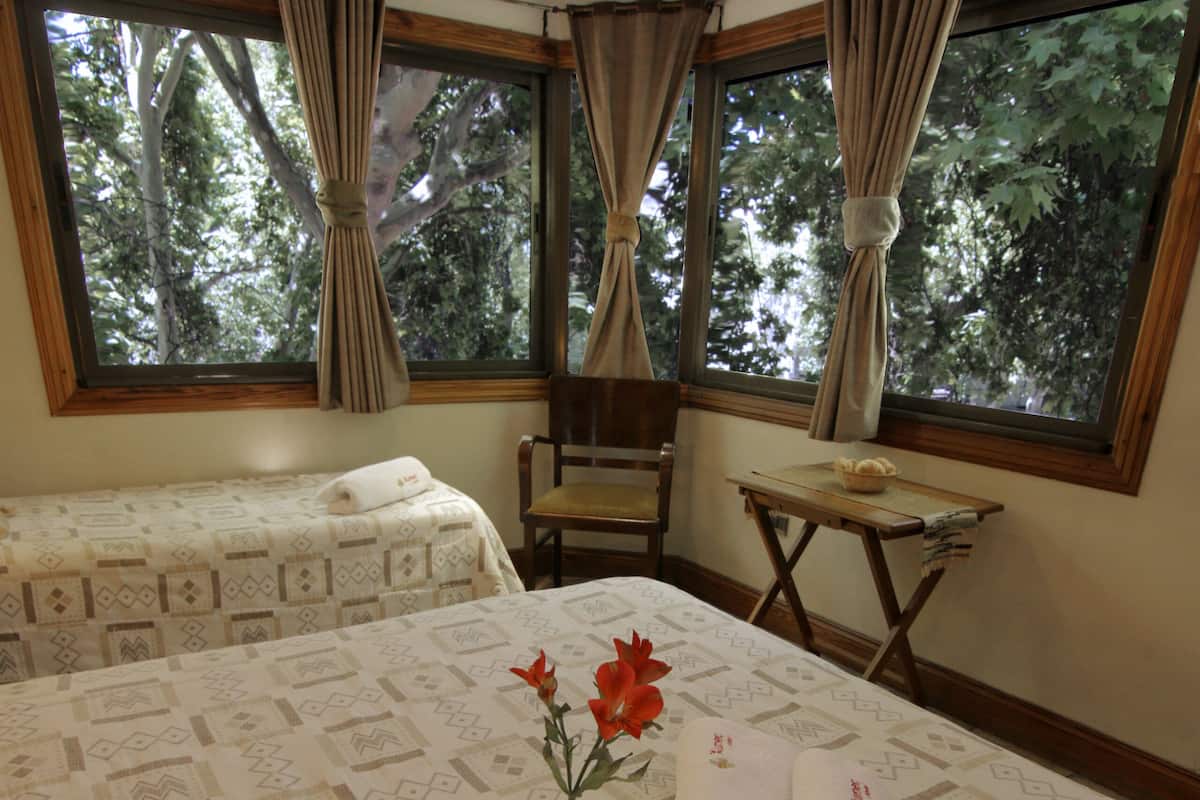 A hotel room with a large bed, a small table with breakfast items, and a window with curtains.