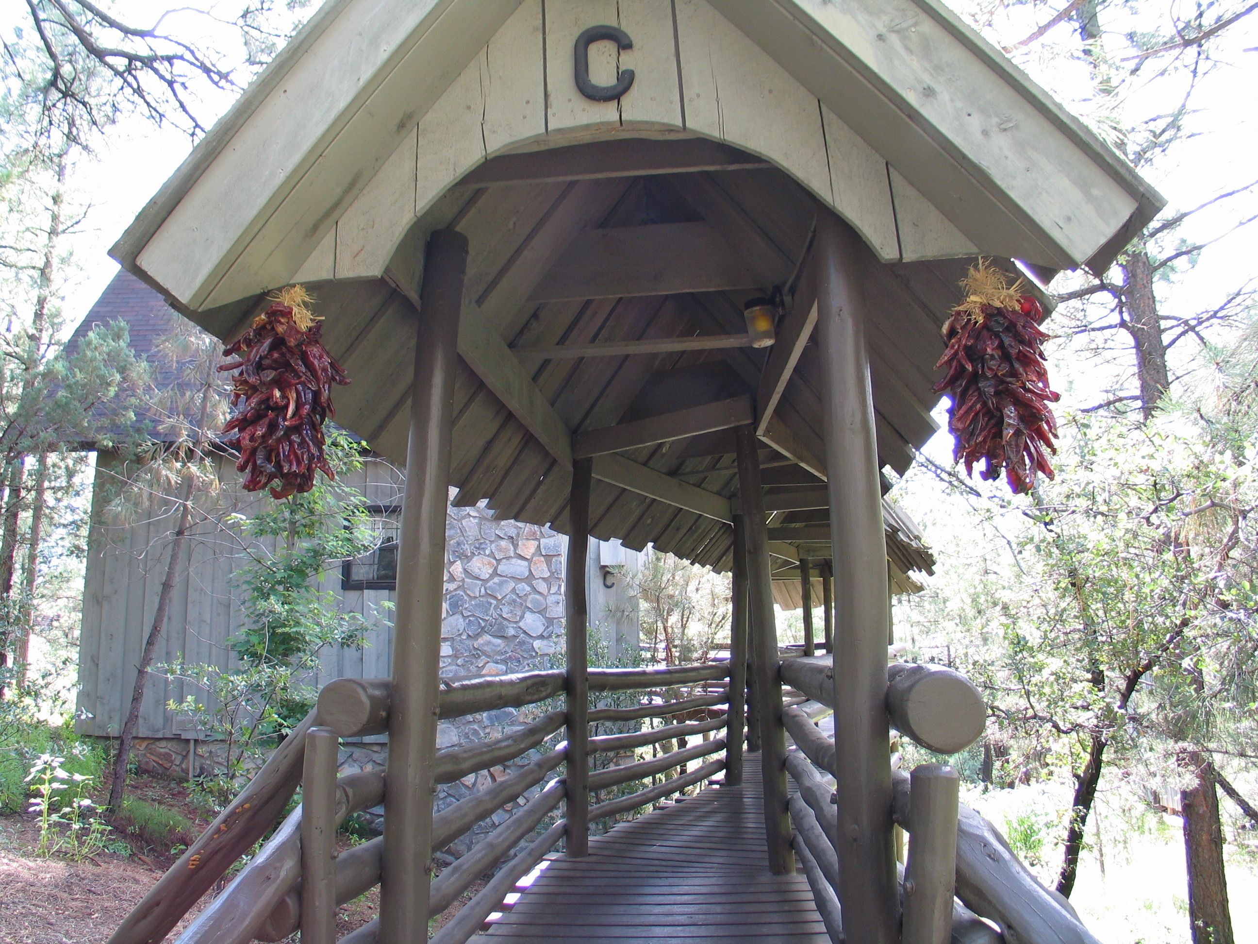 A wooden covered walkway with a stone wall and a wooden building in the background.