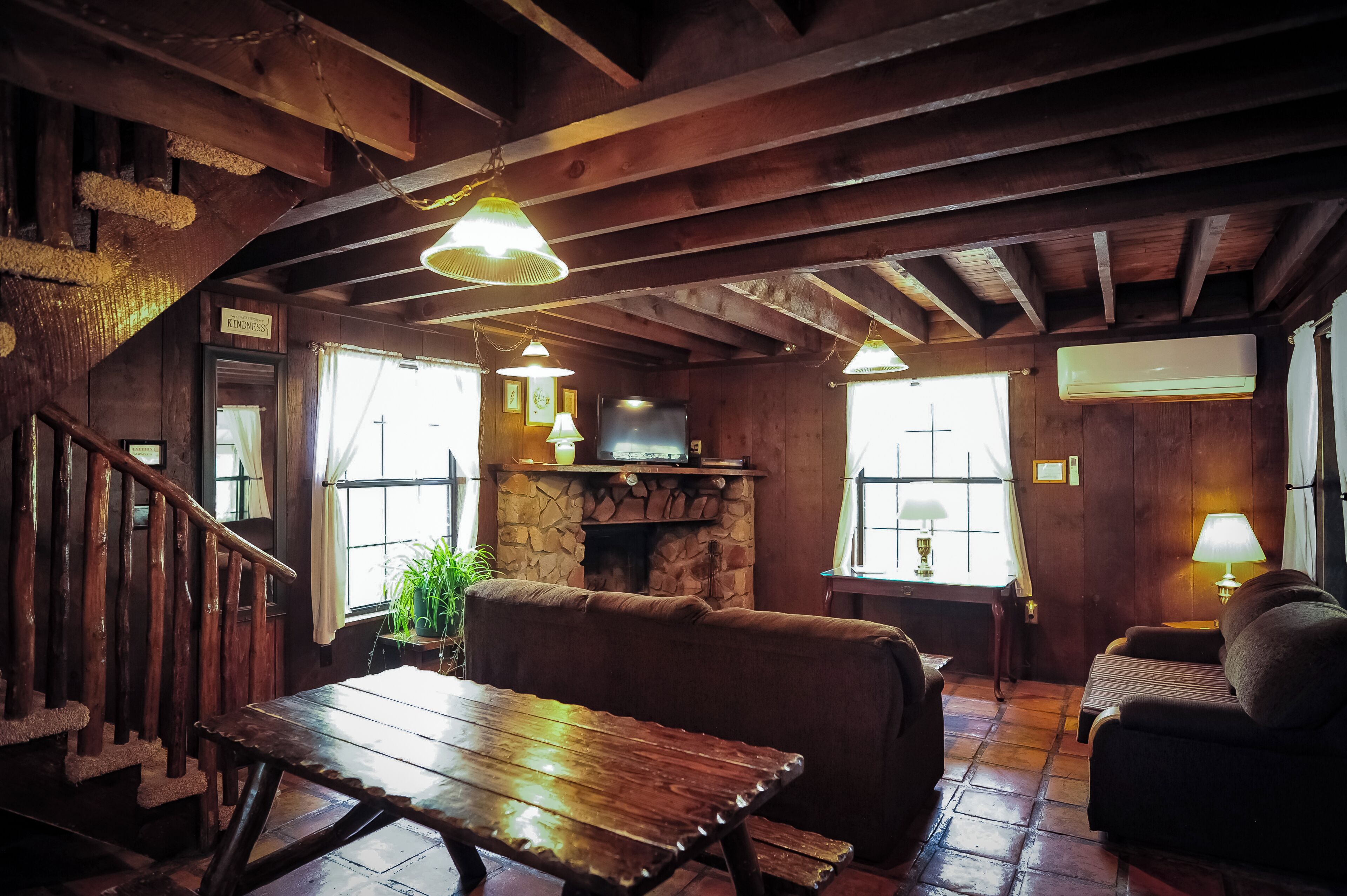 Un interior rústico de madera con chimenea de piedra, escalera de madera y una zona de estar acogedora.