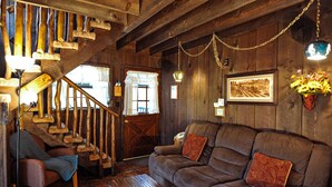 A rustic wooden interior with a staircase, a brown leather sofa, and a wooden bench. - Bear Creek Motel And Cabins (Silver City)