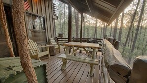 A wooden deck with picnic tables and chairs, surrounded by trees. - Bear Creek Motel And Cabins (Silver City)